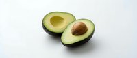 Fresh ripe avocado halves with pit on clean white background isolated for healthy cooking and nutrition design projects.