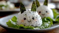 Cute bunny-shaped rice ball with nori seaweed ears and face details on lettuce leaf, Japanese onigiri character food art for children's lunch and bento boxes.