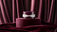 Luxurious burgundy velvet display podium with silver ribbon against draped fabric background creates elegant product presentation setting for jewelry or luxury items.