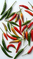 Colorful hot chili peppers scattered on white background. Fresh spicy vegetables in red, green, orange colors for cooking and culinary projects.