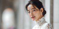 Young Asian woman in elegant white lace blouse with high collar looking over shoulder in soft natural light for fashion and lifestyle content.
