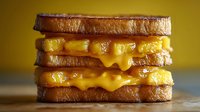 Melted cheese sandwich with golden-brown toasted bread stacked in layers, dripping cheese filling against yellow background, close-up macro food photography.