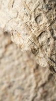 Weathered rope with frayed fibers and natural hemp texture showing wear and aging against blurred stone background for nautical and rustic design projects.