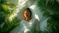 Young African American woman relaxing under palm leaves with dappled sunlight creating shadow patterns on white wall, wellness and mindfulness concept.