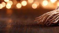 Dried wheat stalks on rustic wooden surface with warm golden bokeh lights creating cozy autumn atmosphere. Natural organic harvest concept.