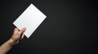 Male hand holding blank white card against dark background, suitable for advertising, branding, marketing campaigns, and promotional materials.