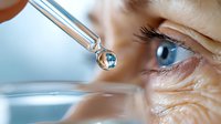 Close up view of eye drop falling from pipette with water reflection and blue iris in background, medical eye care treatment concept for ophthalmology and vision health.