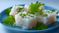 Fresh raw white fish fillets garnished with green parsley on blue plate, ready for cooking. Healthy seafood ingredient for culinary preparation.