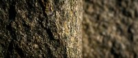 Rough textured concrete wall surface with natural lighting creating depth and shadow patterns for industrial architecture and construction backgrounds.