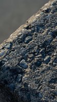 Close-up macro view of rough textured rock surface with pebbles and mineral formations showing natural geological patterns and weathered stone details.
