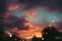 Romantic sunset sky with heart-shaped bokeh lights and dramatic colorful clouds creating dreamy atmosphere for Valentine's Day designs and love themes.