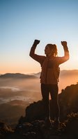 Successful woman hiker celebrating victory with raised arms at mountain summit during golden hour sunrise with scenic valley landscape below.