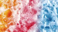Colorful soap foam bubbles in orange pink and blue creating vibrant cleaning background with rich lather texture for hygiene and freshness concepts.
