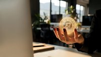 Professional businessman holding glowing golden cryptocurrency coin in modern office workspace representing digital finance and blockchain investment opportunities.