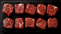 Raw ribeye steaks arranged on dark slate board showing marbled beef cuts ready for grilling, cooking or barbecue preparation in kitchen or restaurant.