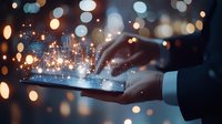 Male hands holding digital tablet displaying glowing futuristic cityscape hologram with sparkles and bokeh lights, representing smart city technology and innovation.
