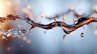 Dynamic liquid splash with water drops suspended in air against soft bokeh background, capturing motion and transparency in macro photography.