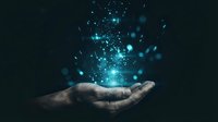 Open palm holding glowing blue digital particles and light effects against dark background for technology and innovation concepts.