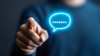 Male hand pointing at glowing blue neon chat bubble icon floating in dark space, representing digital communication and messaging technology for business concepts.