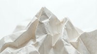 Crumpled white paper texture with angular folds and peaks, isolated on light background. Suitable for design, packaging, and creative projects.