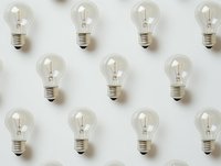 Clear glass light bulbs arranged in neat rows on white background, creating minimalist pattern for business innovation and creative concepts.