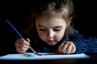 Young girl concentrating while painting with watercolors on paper, creative art activity for children's education and artistic development.