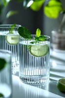 Fresh mojito cocktail with lime slice and mint leaves in elegant ribbed glass on reflective surface. Refreshing summer drink in natural light.
