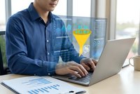 Young businessman analyzing data funnel visualization on laptop screen with digital marketing analytics dashboard in modern office environment.