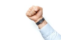 Raised fist of person wearing smart fitness tracker and light blue business shirt sleeve on white background, isolated photo for design and commercial use.