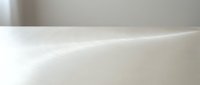 Close-up of smooth white ceramic bathtub rim with soft lighting, showcasing curved edge and glossy finish for bathroom design and home decor projects.