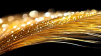 Golden feather with sparkling water drops and bokeh lights on black background creates magical atmosphere with soft focus and dreamy effect.