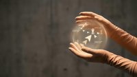 Close-up of hands holding transparent glass sphere with glowing arrows inside, symbolizing growth, success, and business strategy on blurred background.