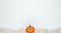 Carved jack-o-lantern pumpkin with glowing face isolated on white background with crumpled paper, perfect for seasonal marketing and autumn holiday designs.