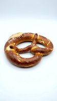 Freshly baked pretzel with coarse salt crystals on white background, ready for food photography, bakery marketing, or culinary design projects.