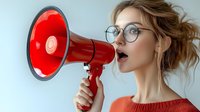 Young blonde woman with glasses speaking into red megaphone for communication and announcement concepts in business marketing campaigns.