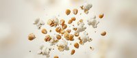 Flying popcorn kernels and fluffy white popped corn scattered in mid-air against soft beige background for snack and entertainment concepts.