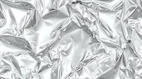 Crumpled silver metallic foil texture with reflective wrinkled surface creating abstract shiny background for modern design projects and creative applications.