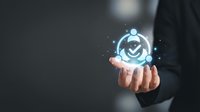 Businessman holding glowing digital checkmark icon with network connections, representing approval, quality assurance, and successful verification for business and technology concepts.