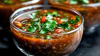 Hearty lentil soup with fresh herbs and vegetables in glass bowl. Nutritious comfort food for healthy eating and meal preparation.