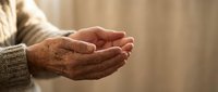 Elderly hands cupped together in prayer or meditation gesture, showing wrinkled skin and age spots. Concept of spirituality, hope, faith, and senior wellness.