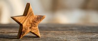 Wooden star decoration with natural grain pattern on rustic table surface for crafts and home decor projects.