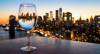 Wine glass with city skyline reflection at sunset creating elegant urban dining atmosphere for restaurant marketing and hospitality concepts.