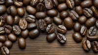 Fresh roasted coffee beans scattered on rustic wooden background, macro shot showing rich brown color and natural texture of arabica beans for cafe menu design.