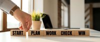 Business strategy concept with wooden blocks showing workflow process from start to win on office desk.