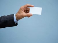 Businessman in dark suit holding blank white card against blue background for corporate branding and business contact presentation.