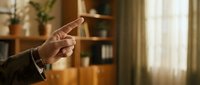Caucasian male hand in suit jacket pointing index finger forward in office interior, concept of direction, leadership, and decision making.