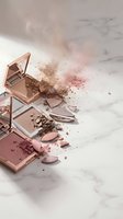 Broken makeup compacts with scattered powder creating artistic mess on marble surface for beauty and cosmetics advertising campaigns.