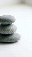 Stack of three smooth gray zen stones balanced on white surface creating peaceful spa atmosphere for meditation and wellness practices.