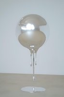Transparent liquid sphere suspended above wooden surface with dripping streams, isolated on white background for design and artistic projects.