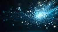 Glowing blue light particles burst with radiant energy against dark background, creating dynamic motion effect for technology and innovation concepts.